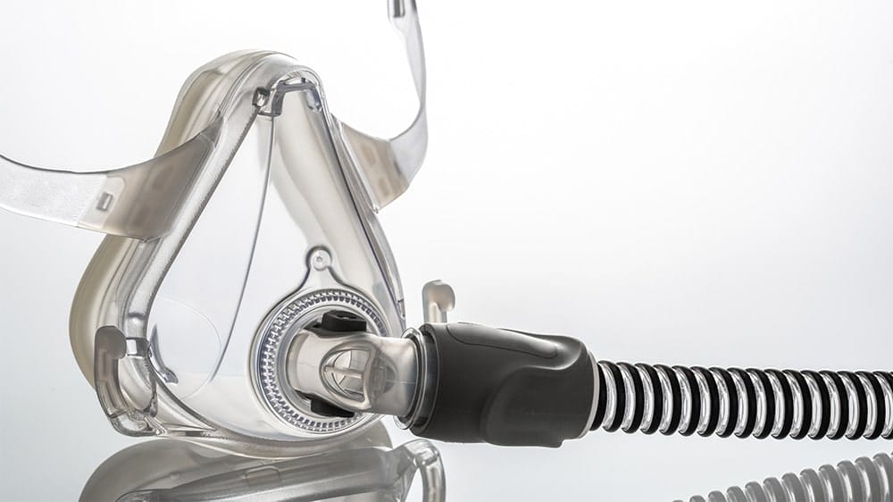 CPAP mask with attached hose on a reflective surface