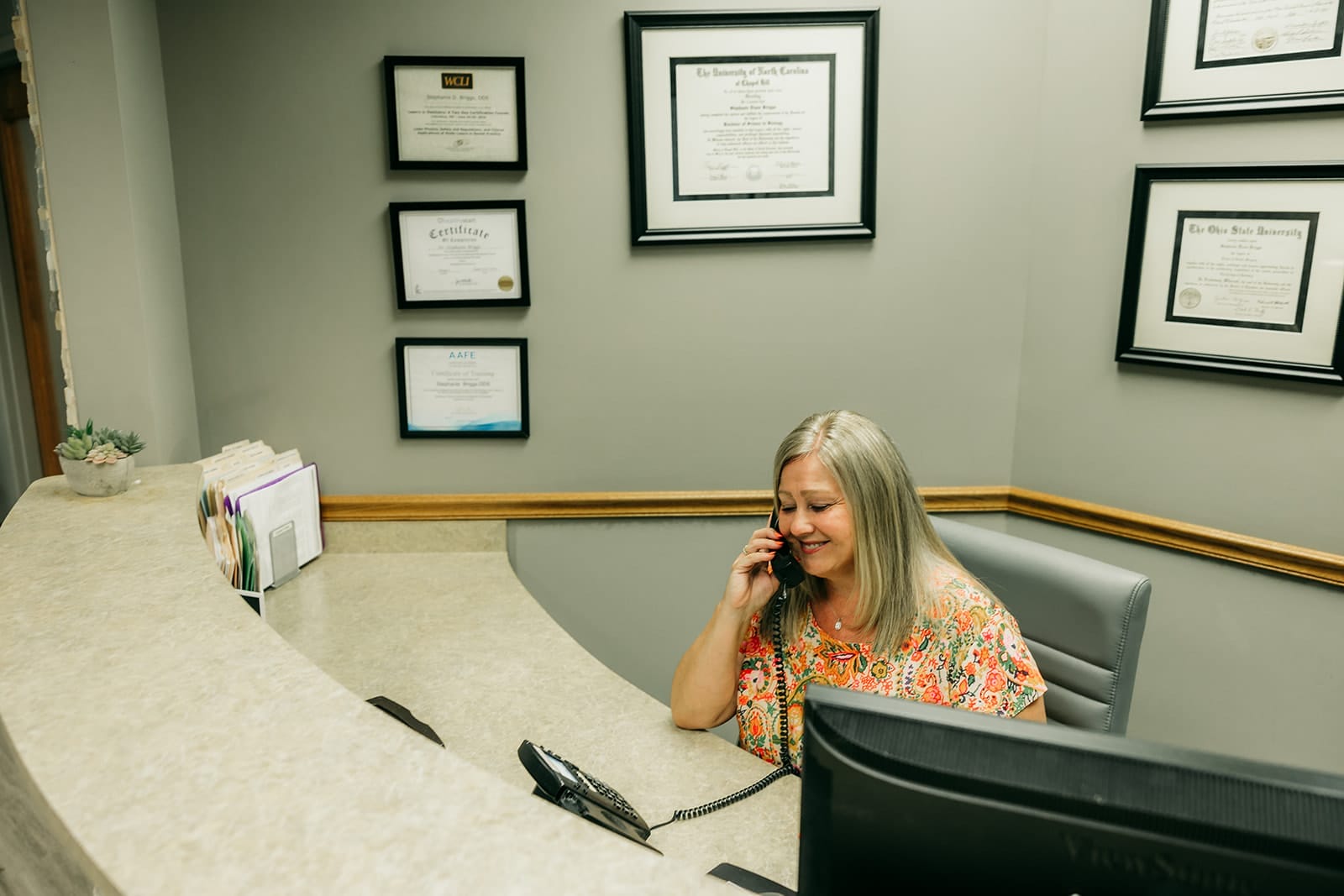 Smiling woman on the phone at a dental office reception desk