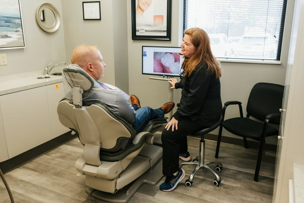 A dentist showing a male patient a close-up dental image on a monitor during a consultation