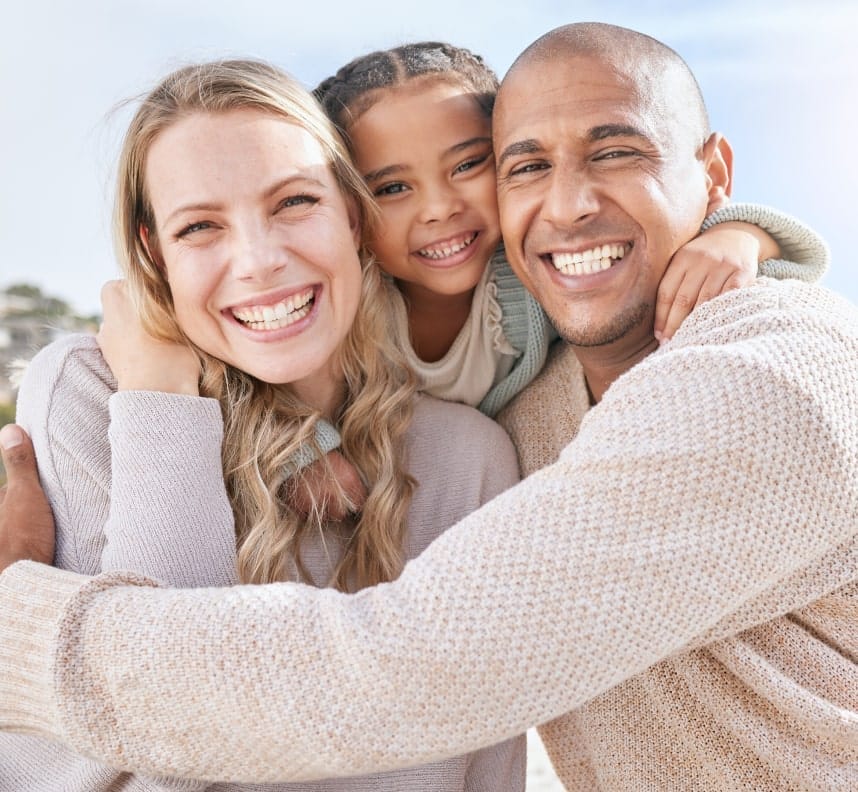Happy family of three smiling together outdoors